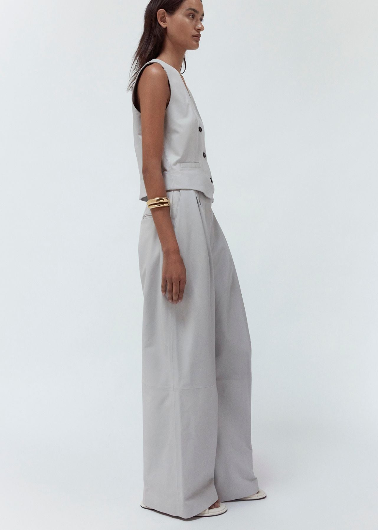 13547 PORTLYN UTZON aw 24 lamb leather pants with wide legs styled with a matching vest and a gold bracelet full body shot model shown from the side