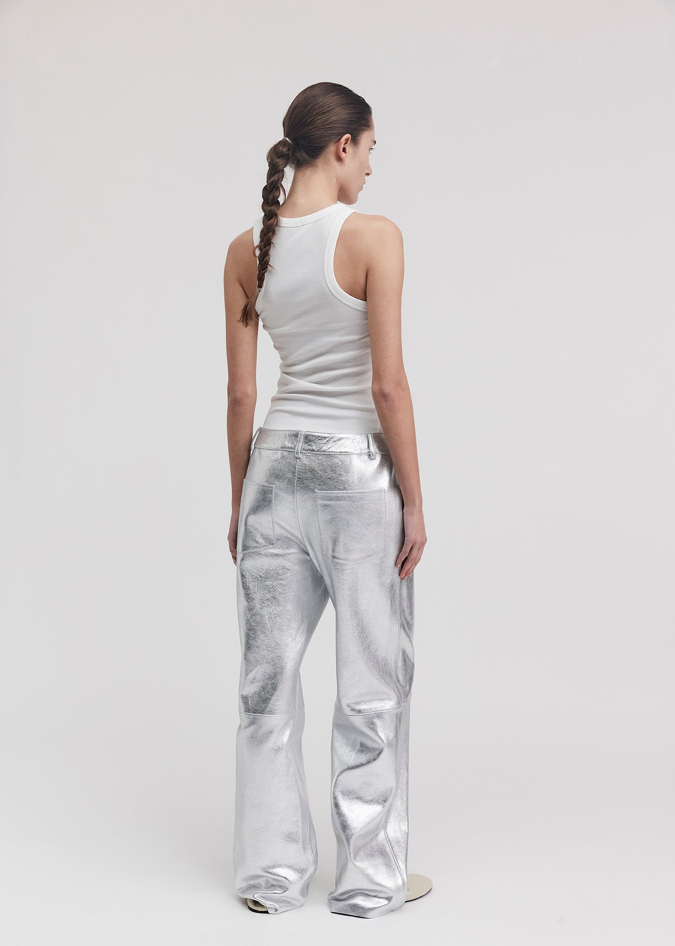 13528 BLANCE UTZON aw24 silver leather pants styled with a white tanktop from back model looking sideways